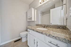 Bathroom with baseboards, tile patterned flooring, toilet, vanity, and a shower