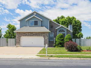 Traditional-style home featuring concrete driveway, an attached garage, a chimney, and brick siding