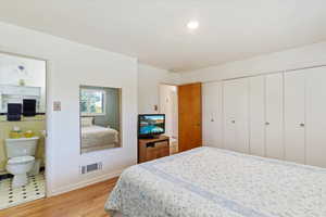 Primary bedroom featuring light wood-style flooring, ensuite 3/4 bath, baseboards, and lots of closet space