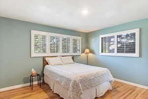 Primary bedroom with baseboards and light colored hardwood finished floors