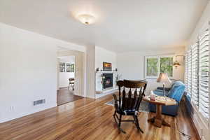 Formal living room with hardwood floors,  large windows with plantation shutters,  radiant-style heat fireplace
