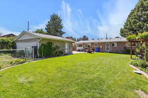 View of yard featuring a patio area, detached 2-car garage, lawn and mature trees