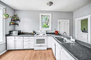 Kitchen featuring white appliances, a sink,, light wood-type flooring, and a textured ceiling