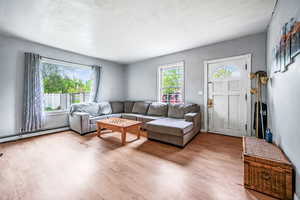 Living room with light wood finished floors and baseboard heating