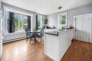 Kitchen featuring white electric stove, a baseboard radiator, a peninsula, a textured ceiling, and dark countertops