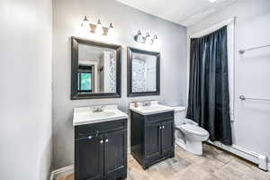 Main bedroom En-suite bathroom with baseboard heating, two vanities, and toilet with skylight.