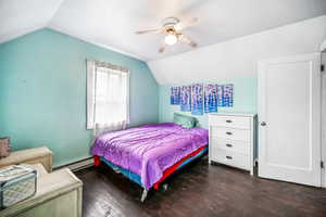 Bedroom with baseboard heating, lofted ceiling, dark wood-type flooring, and ceiling fan