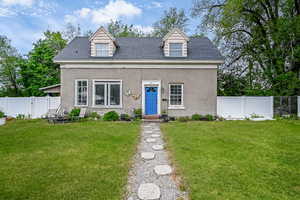 Cape cod home featuring a shingled roof and stucco siding