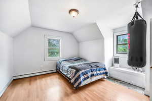 Bedroom with a baseboard radiator, vaulted ceiling, and wood finished floors