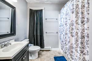 Main Bedroom En-suite bathroom with a baseboard radiator, toilet, vanity, and curtained shower