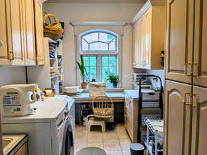 Laundry area with cabinet space, washing machine and dryer, and light tile patterned floors