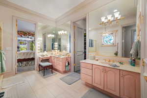 Ensuite bathroom featuring a chandelier, tile patterned floors, two vanities, and ornamental molding