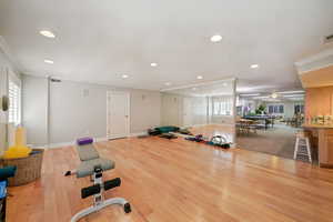Exercise room featuring ornamental molding, recessed lighting, and light wood-style flooring