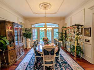 Dining room with a decorative wall, a chandelier, wood finished floors, and ornamental molding