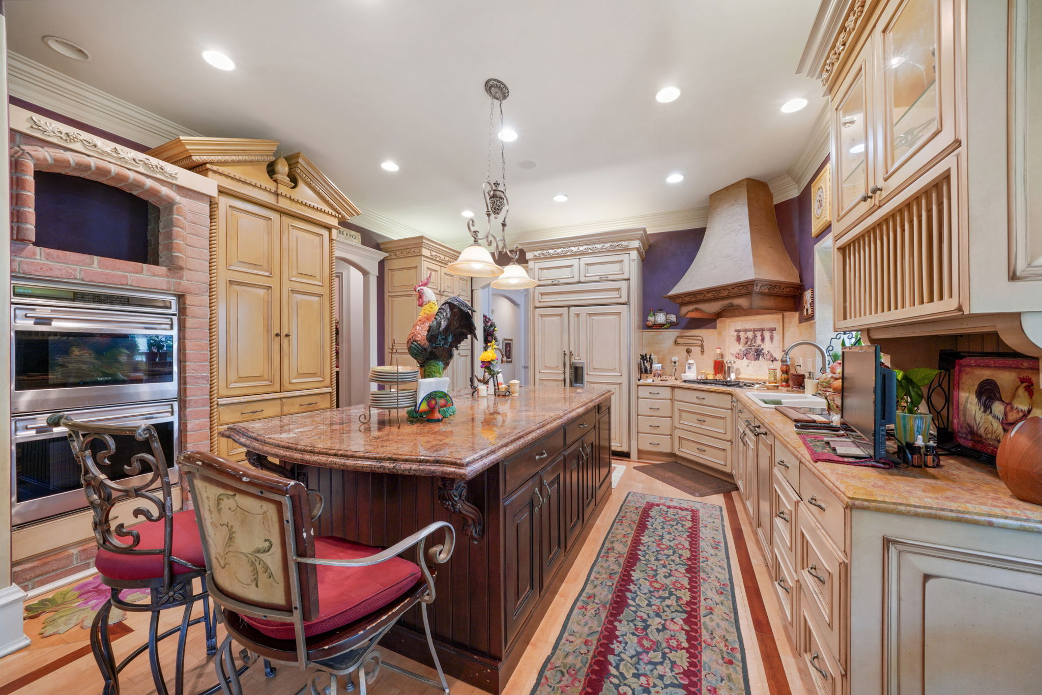 Kitchen with ornamental molding, stainless steel double oven, a center island, light stone countertops, and a breakfast bar