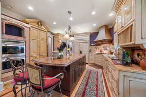 Kitchen with ornamental molding, stainless steel double oven, a center island, light stone countertops, and a breakfast bar