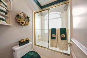 Full bathroom featuring toilet and combined bath / shower with glass door