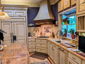 Kitchen with premium range hood, a sink, cream cabinetry, stainless steel gas cooktop, and tasteful backsplash