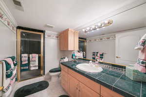 Bathroom with vanity, a stall shower, and ornamental molding