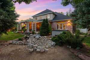 Back of property featuring a hot tub, a pergola, a shingled roof, brick siding, and a patio area