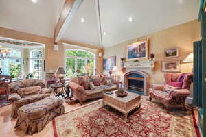 Living area with beamed ceiling, high vaulted ceiling, a glass covered fireplace, a chandelier, and recessed lighting