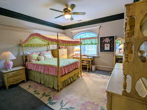 Carpeted bedroom featuring ornamental molding, a ceiling fan, and baseboards