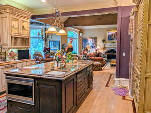 Kitchen with stainless steel microwave, a sink, open floor plan, light wood-type flooring, and cream cabinetry