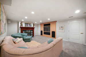Living room featuring recessed lighting, a tiled fireplace, light carpet, and crown molding