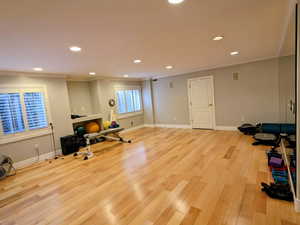 Exercise room with ornamental molding, recessed lighting, light wood-style flooring, and baseboards