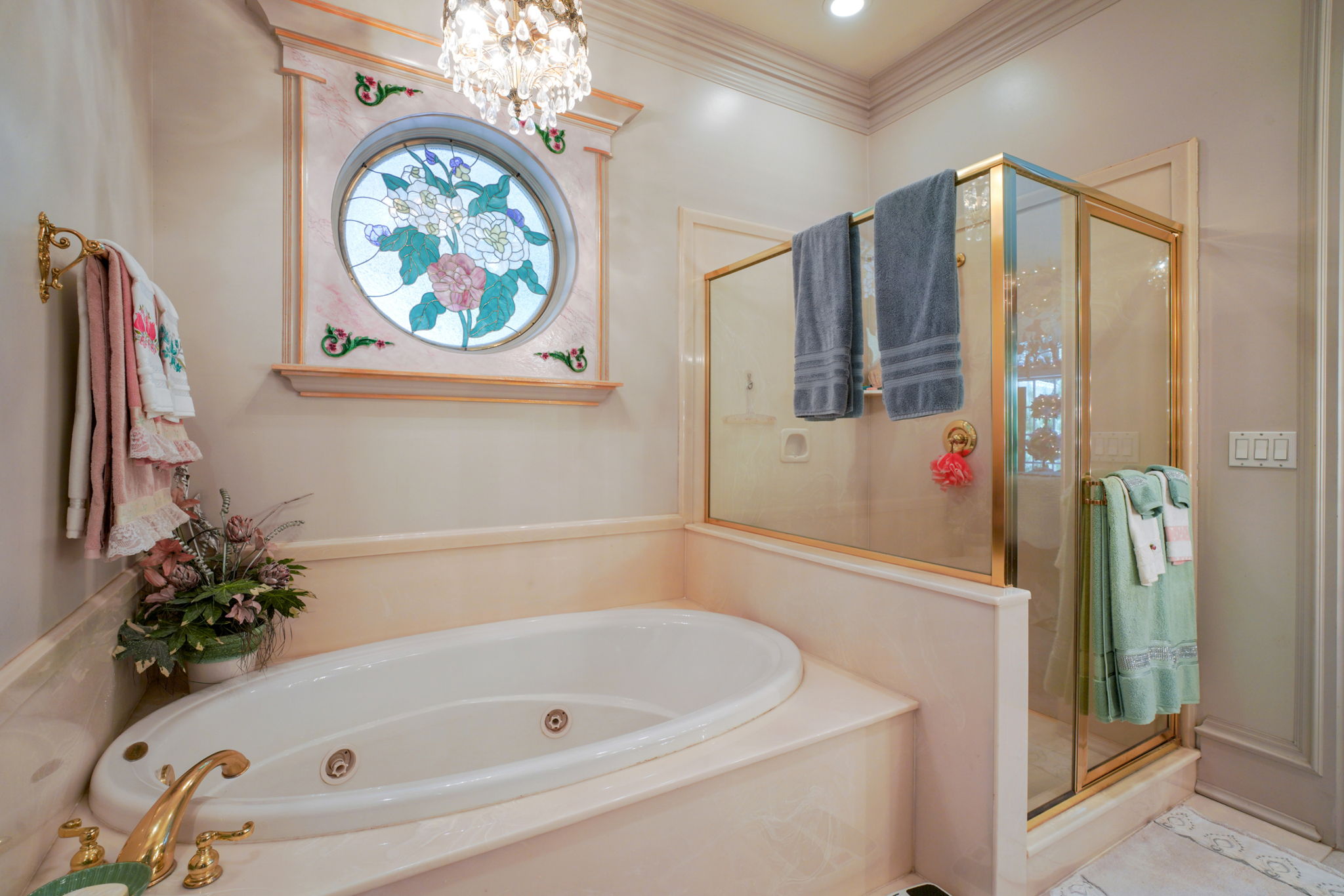 Full bathroom with a shower stall, a tub with jets, a chandelier, and crown molding