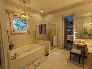 Full bath featuring a shower stall, a jetted tub, a chandelier, vanity, and crown molding