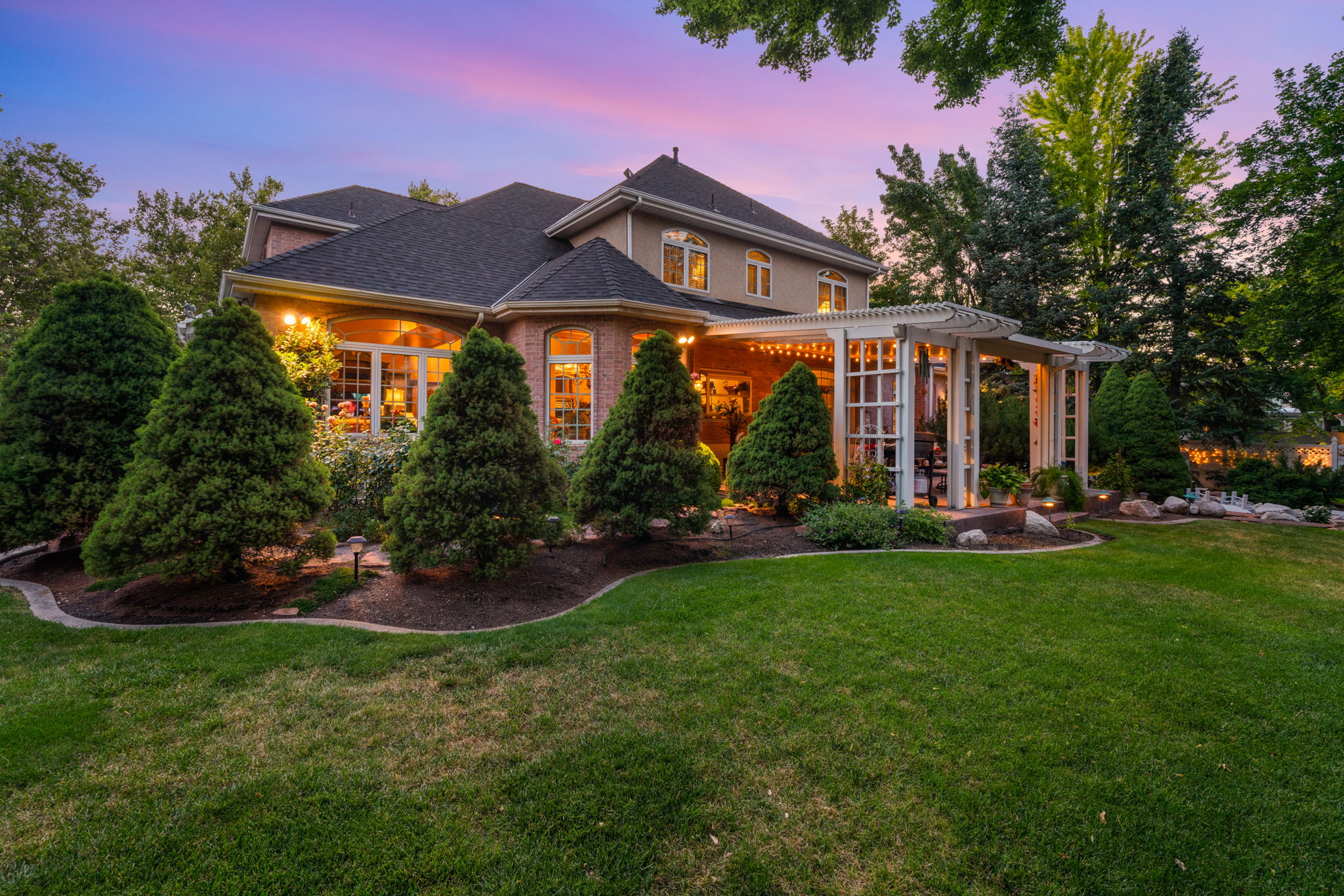 View of front facade with a pergola, a front yard, roof with shingles, and brick siding