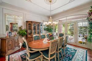 Dining room with french doors, a chandelier, wood finished floors, and a decorative wall