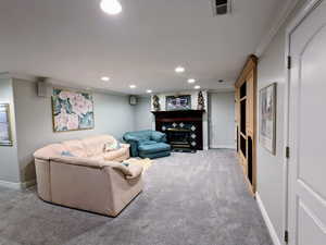 Carpeted living area featuring crown molding, a glass covered fireplace, recessed lighting, and baseboards