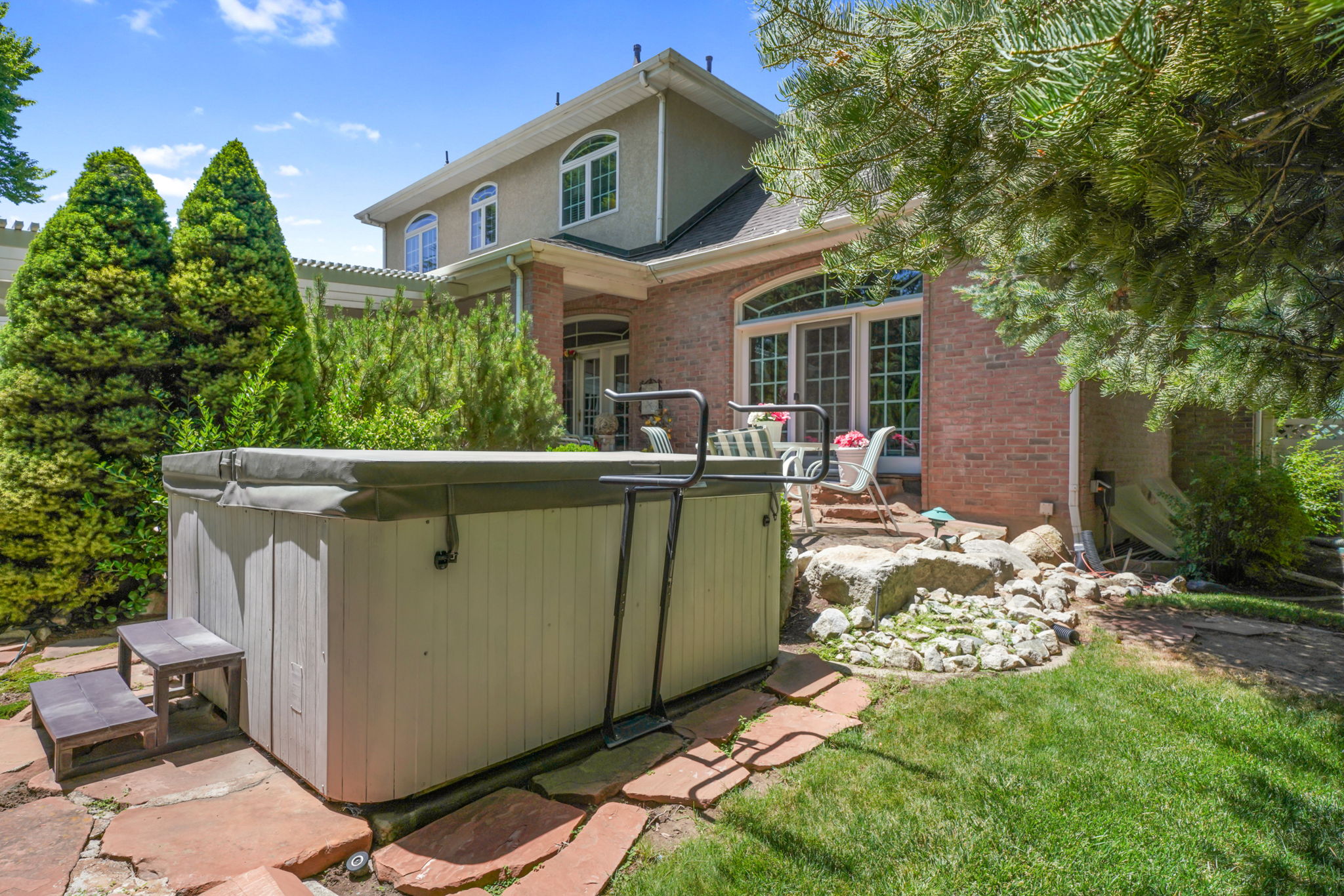 Rear view of house with a hot tub and brick siding
