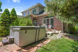 Rear view of house with a hot tub and brick siding