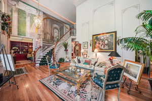 Living area with a high ceiling, stairs, wood finished floors, and a chandelier