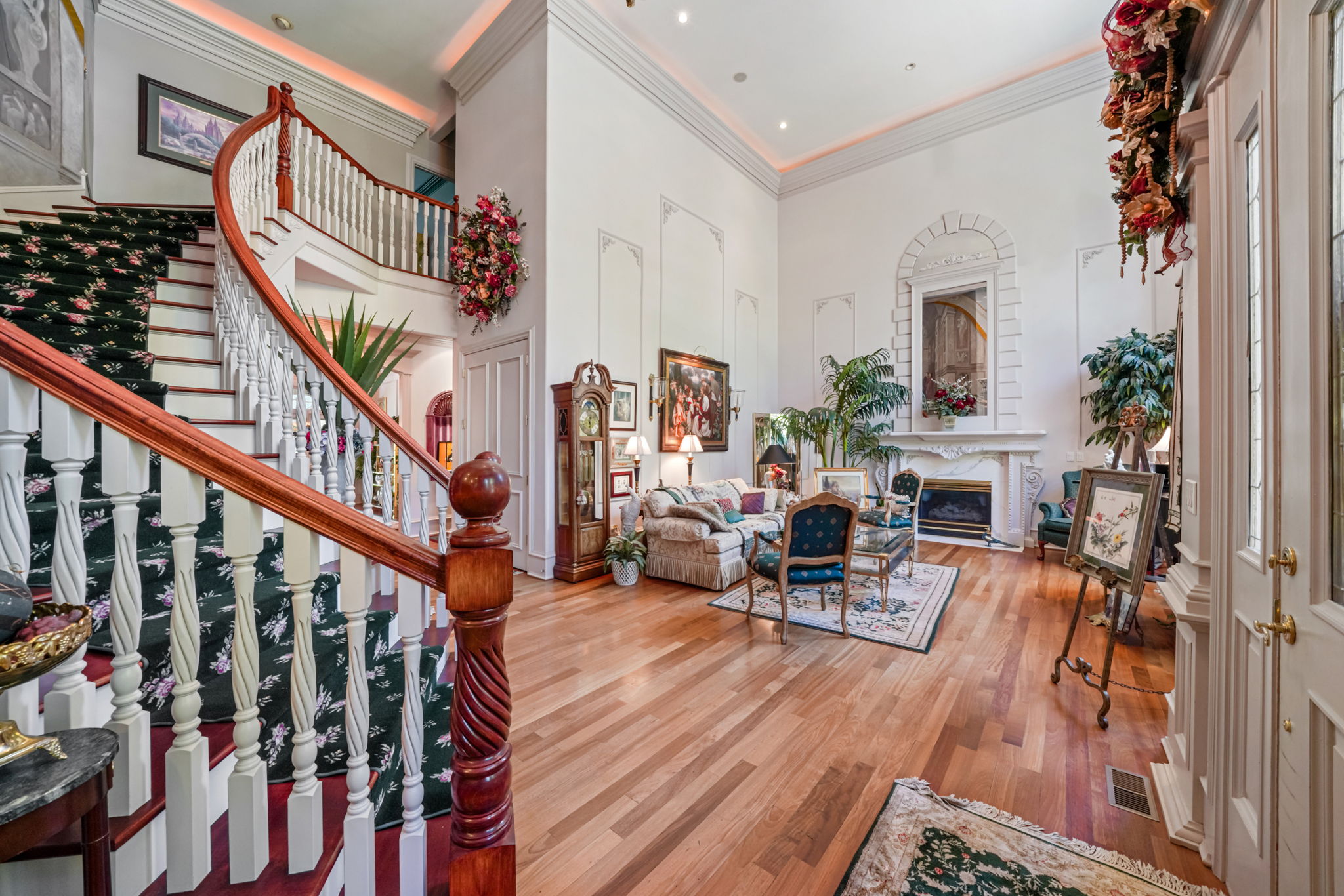 Living area with wood finished floors, stairs, ornamental molding, a towering ceiling, and a premium fireplace