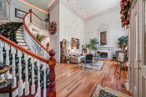 Living area with wood finished floors, stairs, ornamental molding, a towering ceiling, and a premium fireplace