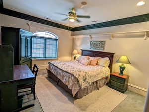Carpeted bedroom with baseboards, crown molding, and ceiling fan