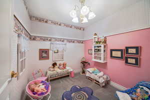 Recreation room with a chandelier, wallpapered walls, and carpet