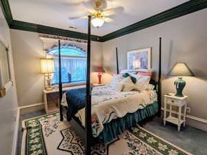 Carpeted bedroom featuring baseboards, ornamental molding, and a ceiling fan