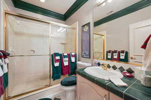 Bathroom with a shower stall, vanity, ornamental molding, tile patterned flooring, and tasteful backsplash