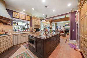Kitchen featuring open floor plan, cream cabinetry, a fireplace, crown molding, and decorative backsplash