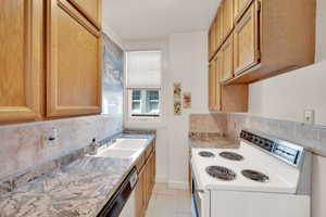 Kitchen featuring white appliances, a sink, tasteful backsplash, light countertops, and light tile patterned floors