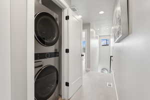 Laundry area featuring stacked washing machine and dryer, carpet flooring, recessed lighting, and baseboards