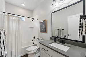 Bathroom with shower / bathtub combination with curtain, vanity, and toilet
