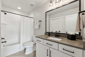 Bathroom featuring toilet, vanity, and shower / bath combo with shower curtain