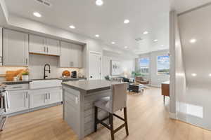 Kitchen featuring a sink, a kitchen island, light wood-style floors, open floor plan, and recessed lighting