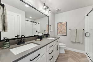 Primary Full bath with a shower stall, toilet, baseboards, double vanity, and recessed lighting
